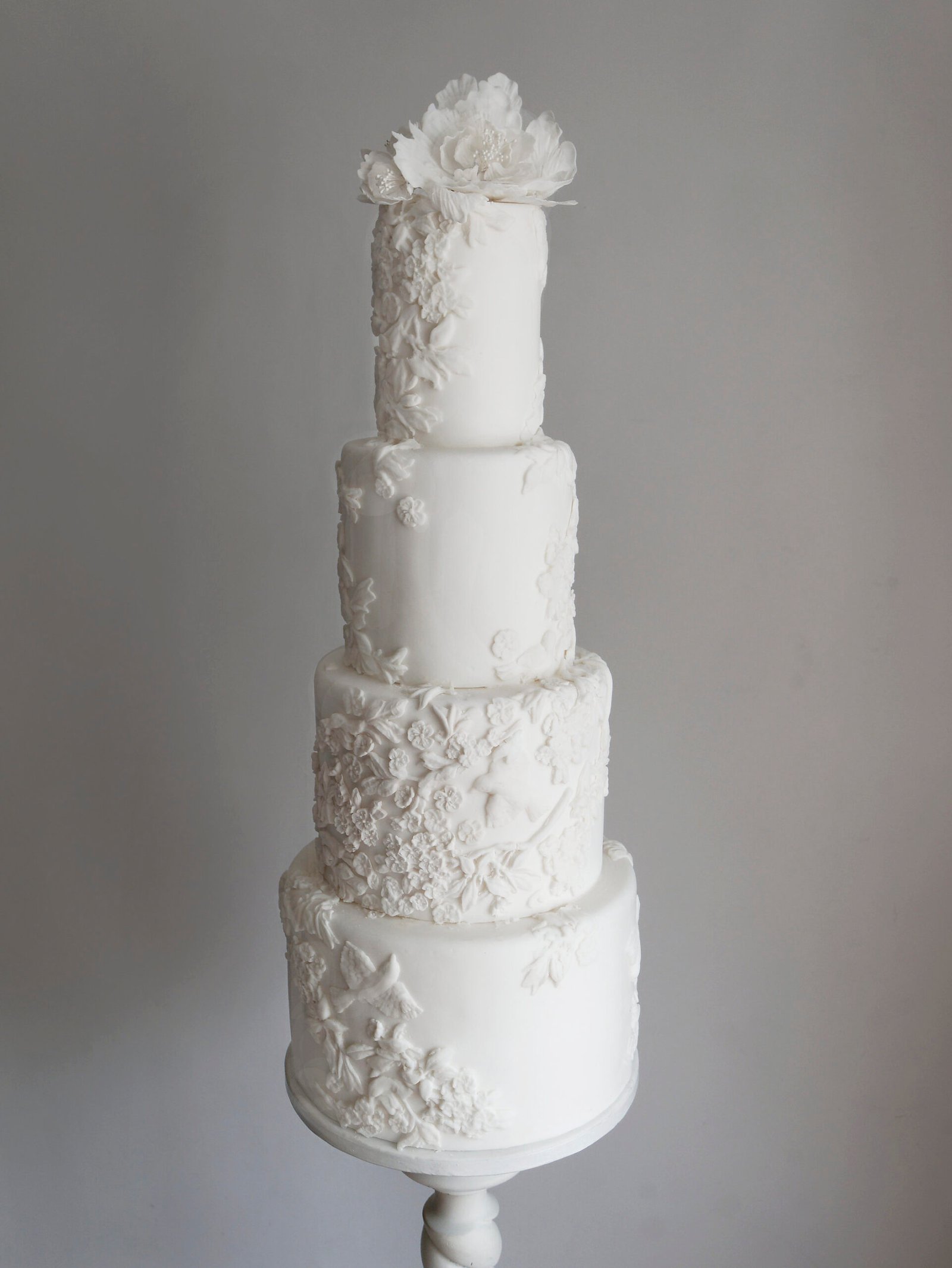 White bas relief wedding cake with flowers and birds