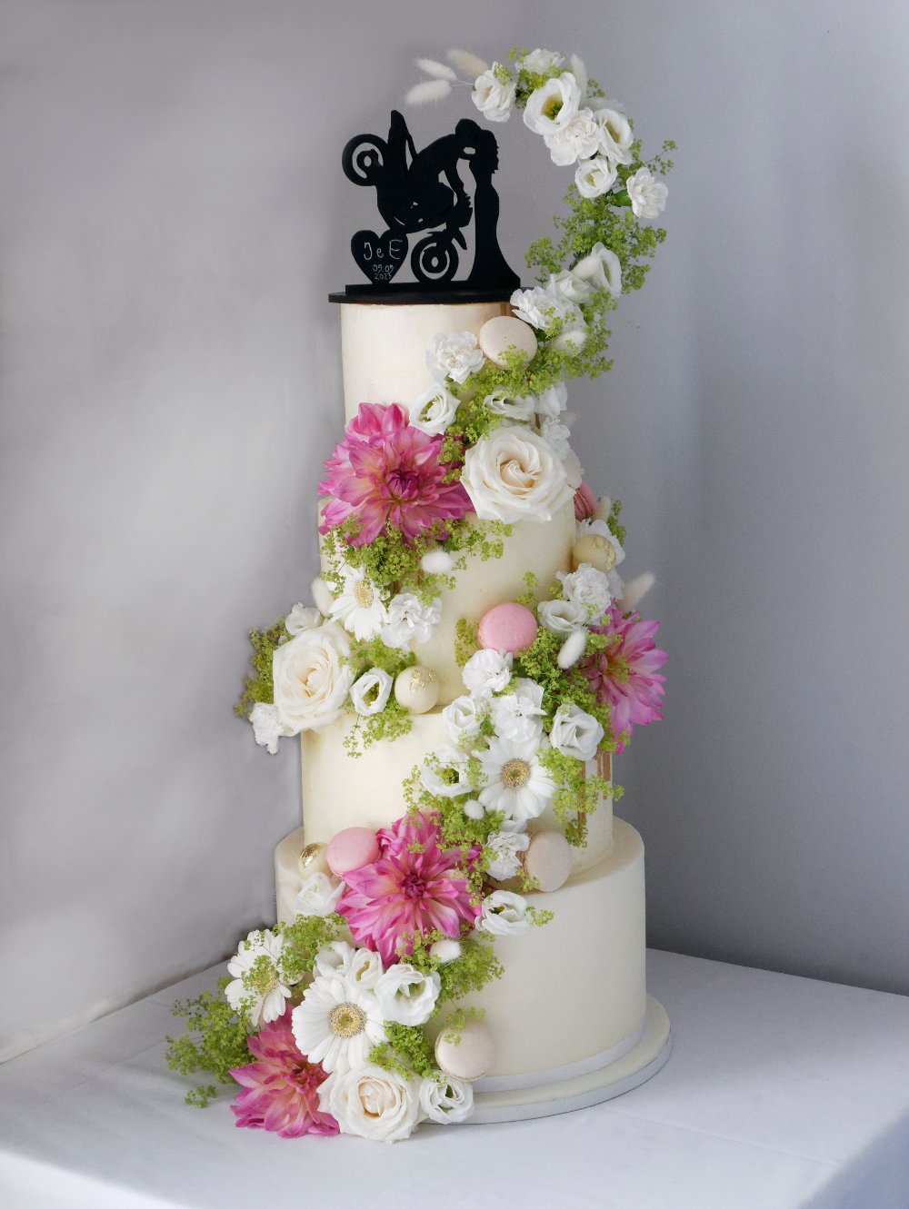 wedding cake with spiral of flowers macarons and mini cakes